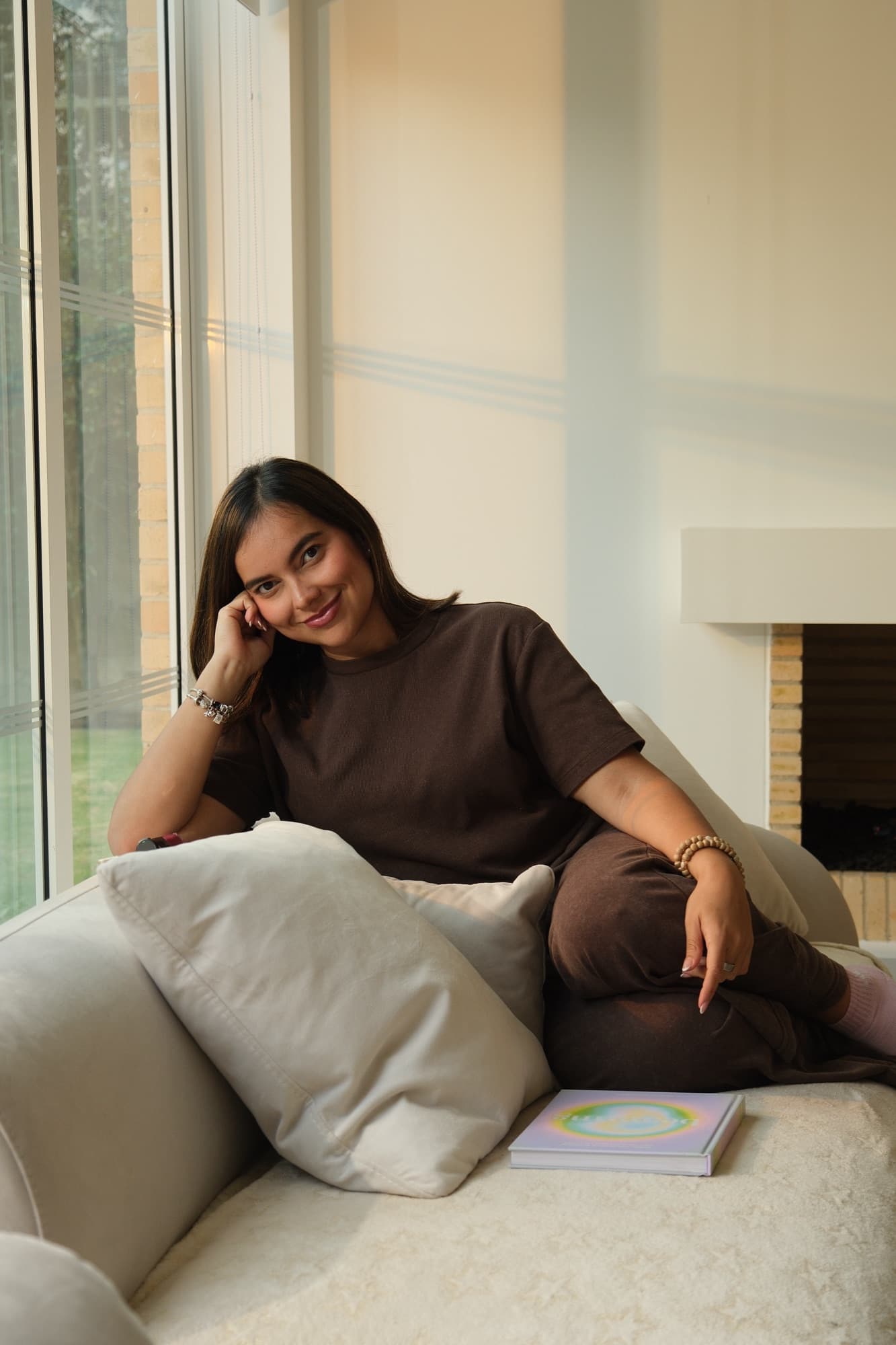 Angélica Cabrera sentada en un sofá junto a un ventanal, con luz de día.